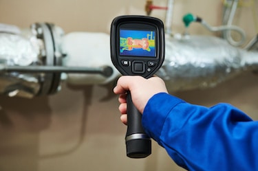 Technician use thermal imaging camera for heat loss inspection and discovering overheating temperature in heating point