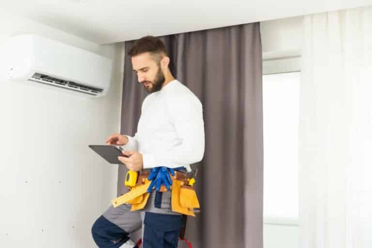 male technician service worker diagnosing for repairs air conditioner. person using tablet