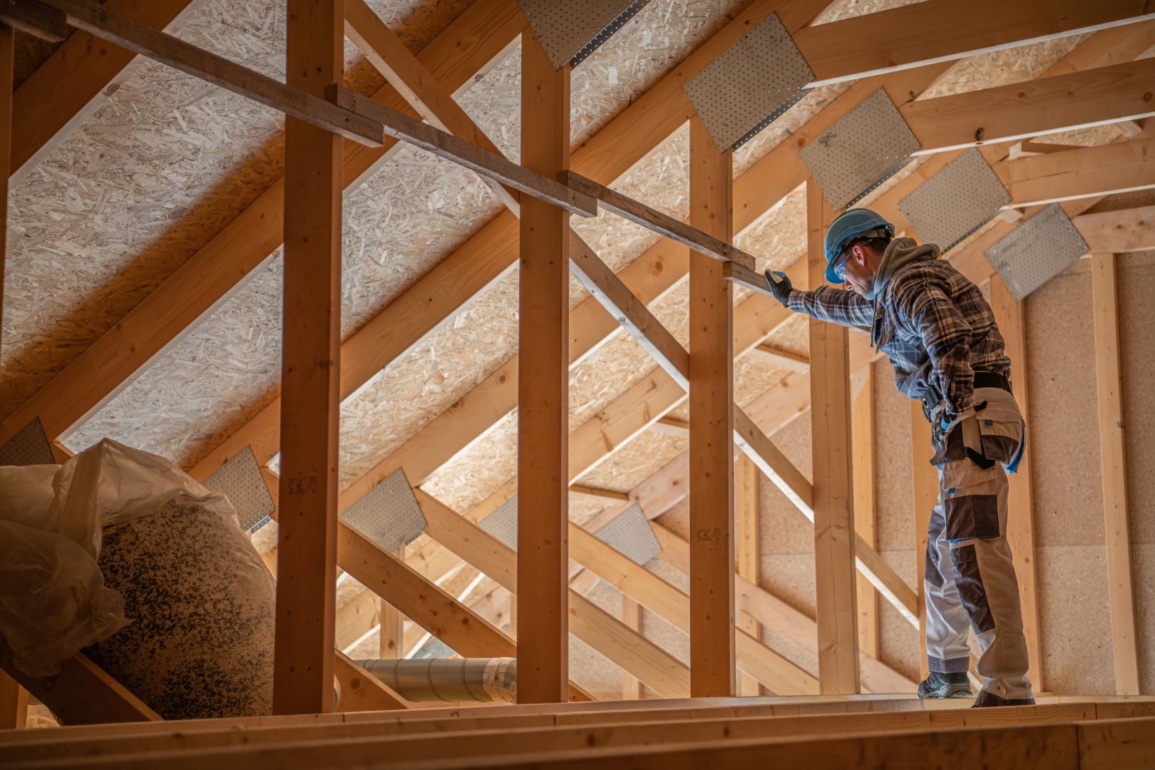 Worker inspecting attic insulation and roof structure
