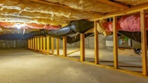 Panorama Basement or crawl space with upper floor insulation and wooden support beams. An area of limited height under the floor of a house with concrete wall and floor.
